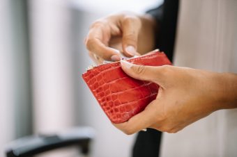 Crop woman taking money from purse Soft focus of unrecognizable female taking banknotes from red leather wallet to pay for purchase